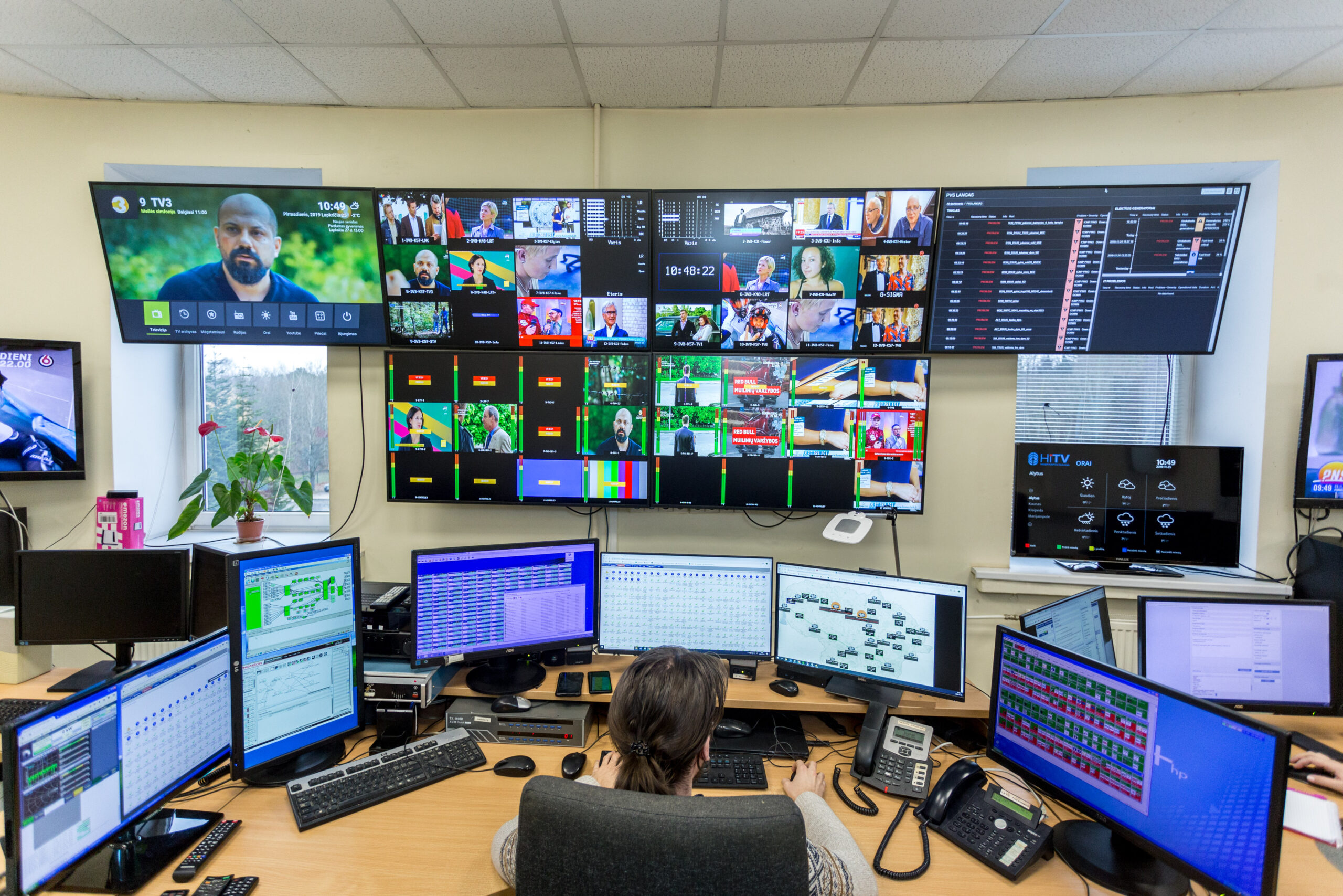 Telecentro transliacijų stebėjimo centras su daugybe monitorių ir operatorius prie pultų